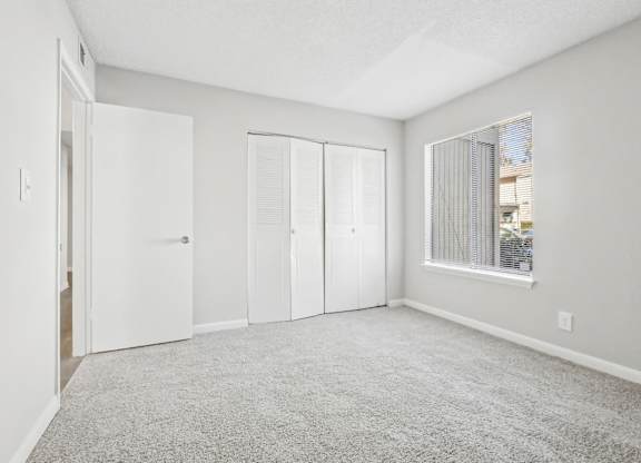 Second bedroom with carpeted floor and sliding doors closet on the side in B1 floor plan at Riverwood Crossing apartments in Roswell, GA..