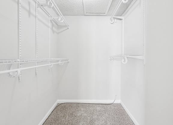 Master bedroom walk-in closet with a carpeted floor and white shelving in C2b floor plan at Riverwood Crossing apartments in Roswell, GA.