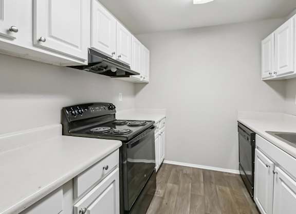 A kitchen with white cabinets and a black stove top oven in B1 floor plan at Riverwood Crossing apartments in Roswell, GA.