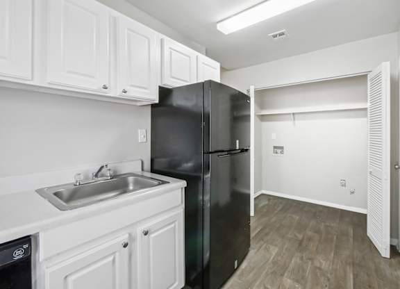 Kitchen with white cabinets and washer and dryer connections in C2b floor plan at Riverwood Crossing apartments in Roswell, GA.