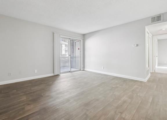Living room with vinyl wood flooring and a sliding door in the B1 floor plan at Riverwood Crossing apartments in Roswell, GA..