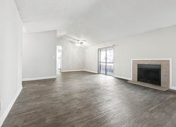 A spacious living room with a fireplace and sliding glass doors in C2b floor plan at Riverwood Crossing apartments in Roswell, GA..