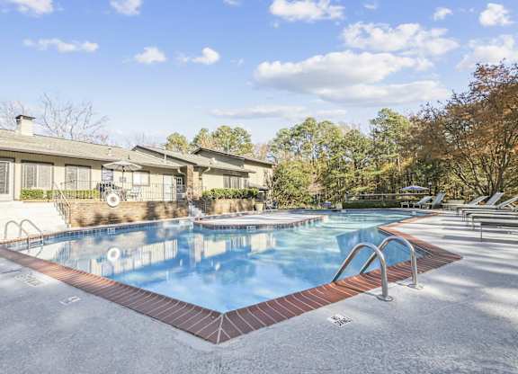 A swimming pool surrounded by a brick border and lounge chairs in autumn at Riverwood Crossing apartments in Roswell, GA.