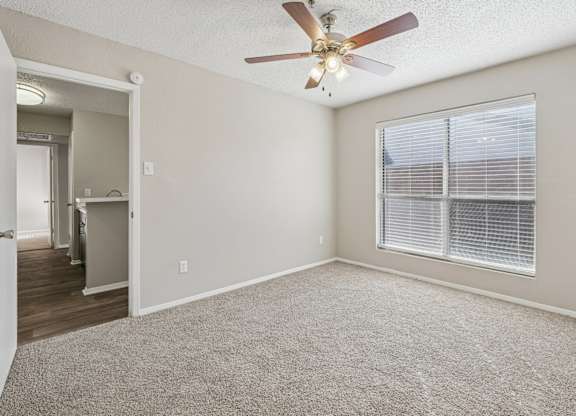 A room with a ceiling fan and carpeted floor.