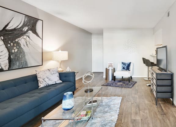 a living room with a blue couch and a glass coffee table