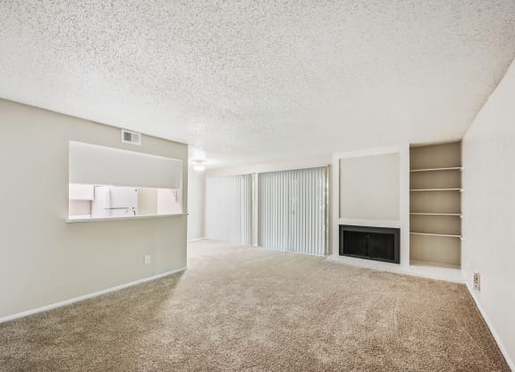 a spacious living room with carpeted flooring and a fireplace