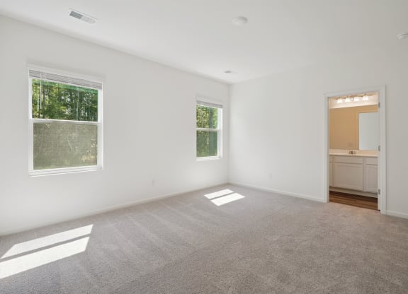an empty bedroom with two windows  and carpets