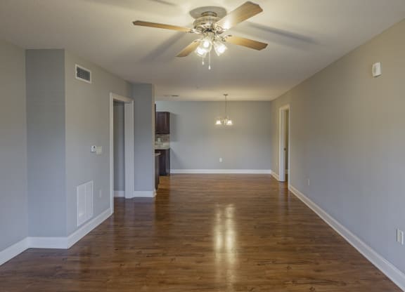 an empty living room with wood floors and a ceiling fan