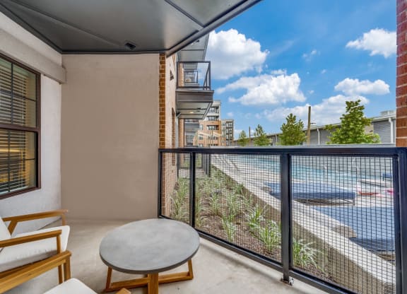 a balcony with a view of a river and a patio with chairs and a table at St. Elmo Apartment in Austin, TX