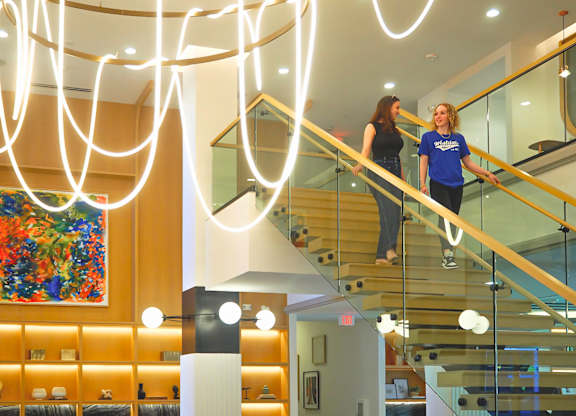 Two women are walking down a staircase at Era Apartments in Denton, TX