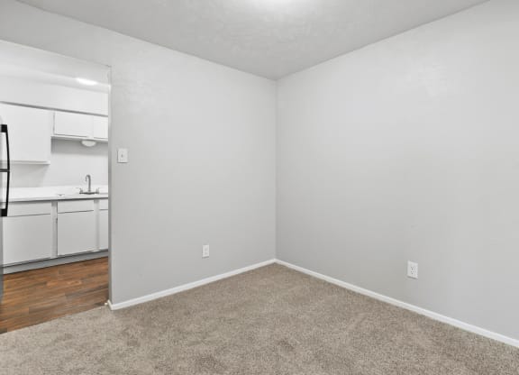 an empty bedroom with a kitchen in the background