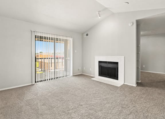 a living room with a fireplace and a door leading to a balcony