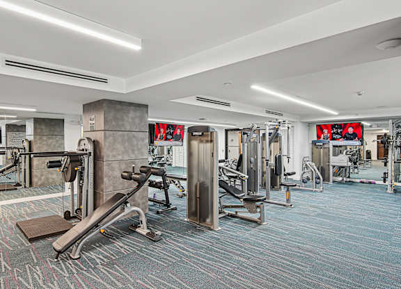 A fitness center with a variety of equipment including a bench press and a squat rack at Twenty2 West luxury apartments in Miami, FL