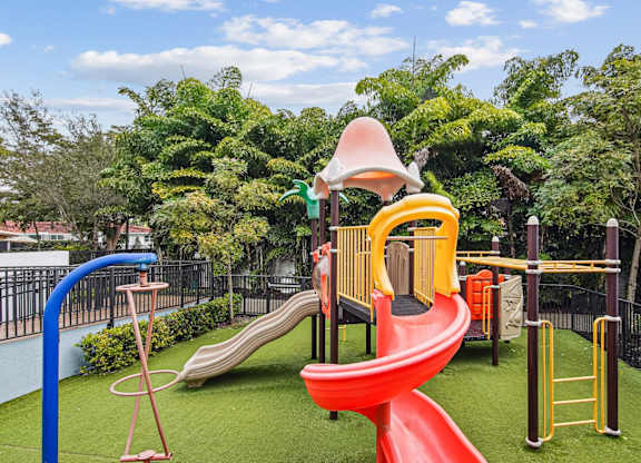 A playground with a red slide and a yellow and green play structure at Twenty2 West luxury apartments in Miami, FL