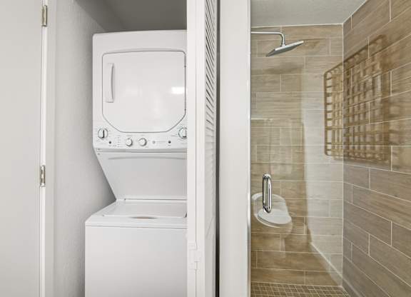 Studio Sixty2 floor plan bathroom with a tiled walk-in shower and stacked washer and dryer at Twenty2 West luxury apartments in Miami, FL