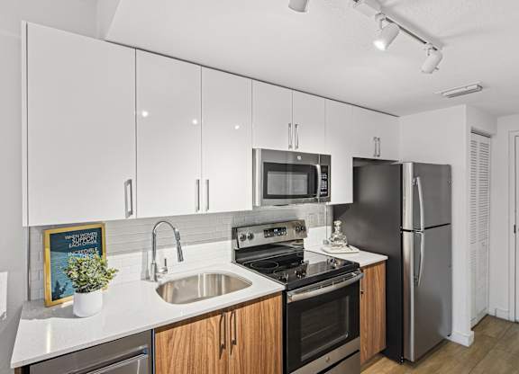 Studio Sixty2 kitchen with white cabinets and stainless steel appliances at Twenty2 West luxury apartments in Miami, FL