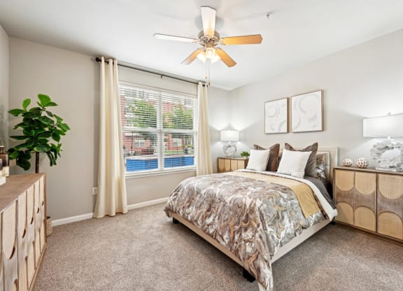 Bright bedroom with ceiling fan and large window at The Grand at Upper Kirby apartments in Houston, TX