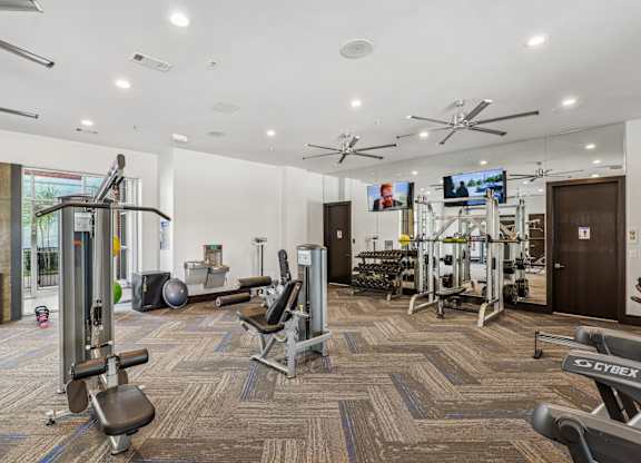 A gym with a variety of equipment including treadmills, weights, and exercise machines.