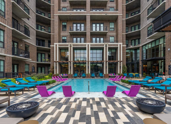 Our sparkling pool with blue loungers and pink in-pool lounge chairs at The Case apartments in Dallas, TX