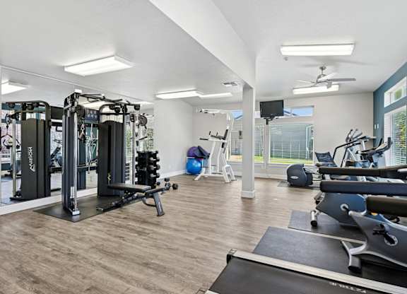 A spacious gym with a variety of equipment including treadmills, weights, and exercise machines at The Madison apartments in Olympia, WA
