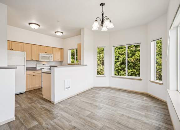A kitchen and dining area with wooden floors and ceiling lights at The Madison Apartments in Olympia, WA
