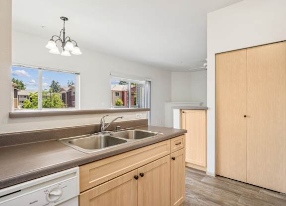 A kitchen with wooden cabinets, a closet, and a sink at The Madison Apartments in Olympia, WA