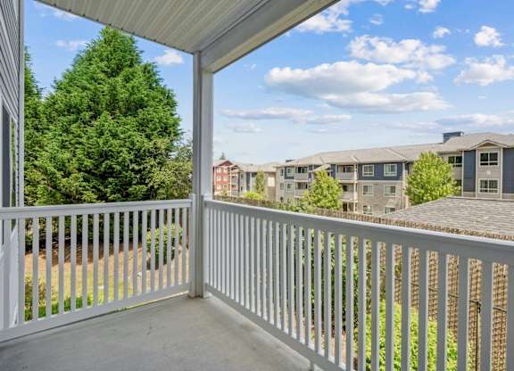 A balcony with a white railing overlooks The Madison Apartments in Olympia, WA