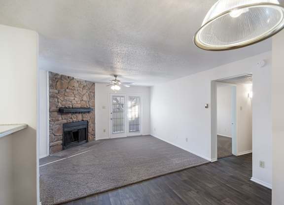 A spacious living room with a stone fireplace and a grey rug.