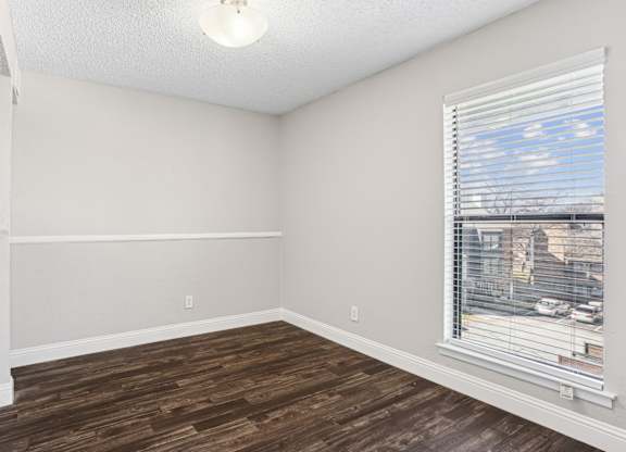 B1 bedroom with a window and wooden flooring at Vine Apartments in Arlington, TX