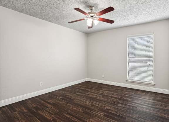 Upgraded A1 bedroom with a ceiling fan and a window with blinds at Vine Apartments in Arlington, TX