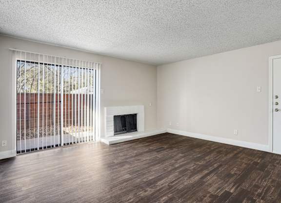 Upgraded A1 living room with a fireplace and wooden floors at Vine Apartments in Arlington, TX