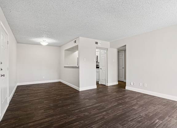 Upgraded A1 living room with wooden floors and white walls at Vine Apartments in Arlington, TX