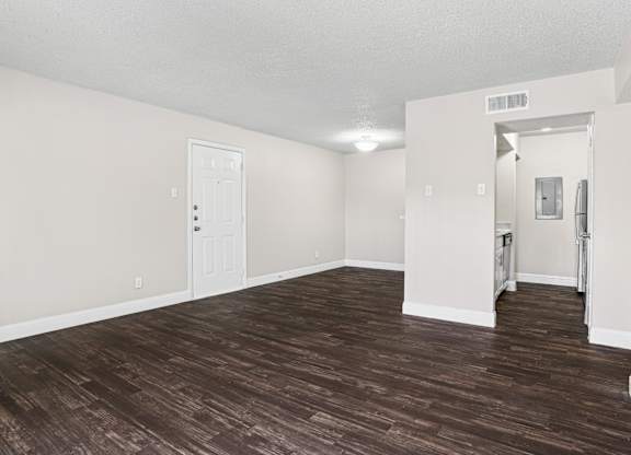 Upgraded A1 living room with a wooden floor and white walls at Vine Apartments in Arlington, TX