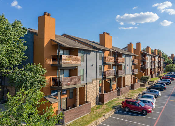 A row of apartment buildings with cars parked in front at Vine Apartments in Arlington, TX