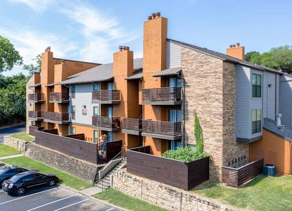 A modern apartment building with a parking lot in front at Vine Apartments in Arlington, TX