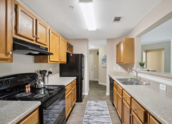 Model apartment kitchen with wood cabinets and black appliances at Wellington Ridge in Lawrenceville, GA