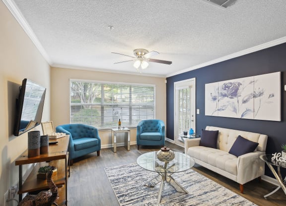 a living room with blue and white furniture and a ceiling fan at Wellington Ridge in Lawrenceville, GA