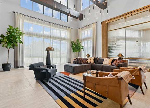 Leasing office lounge space with couches and large windows at Whispering Pines at Westdale Hills in Euless, TX