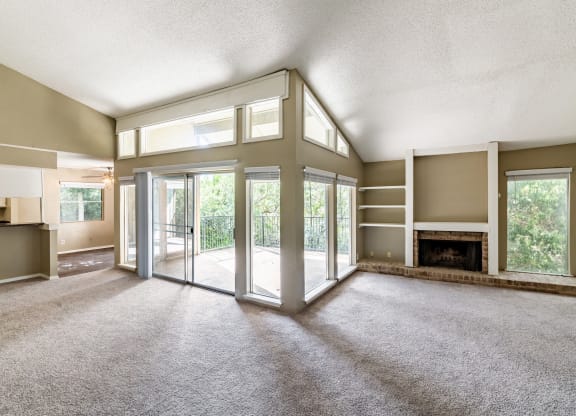 an empty living room with a fireplace and glass doors