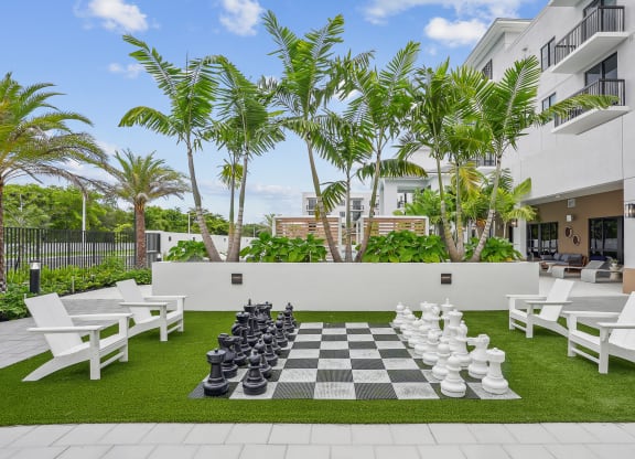 a large chess board is set up on a lawn in front of a building at Westgate on University in Lauderhill, FL