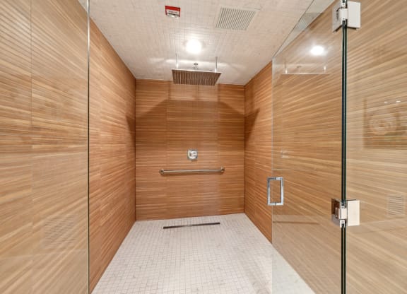Shower area with wooden walls and  glass doors at Westgate on University in Lauderhill, FL