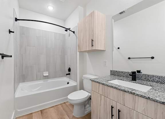Bathroom with light wood vanity, toilet, and shower in B2 apartment at Whispering Pines at Westdale Hills in Euless, TX