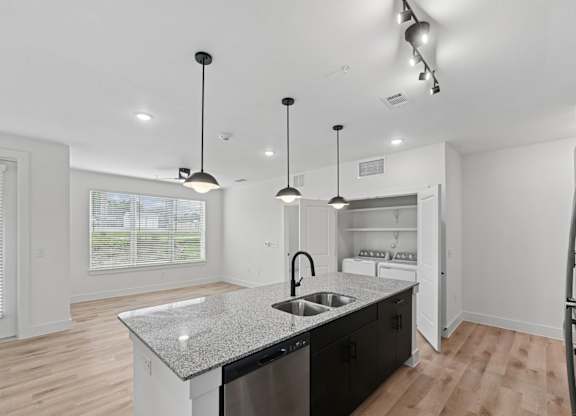 B2 kitchen with a granite countertop and a sink and hanging lights at Whispering Pines at Westdale Hills in Euless, TX