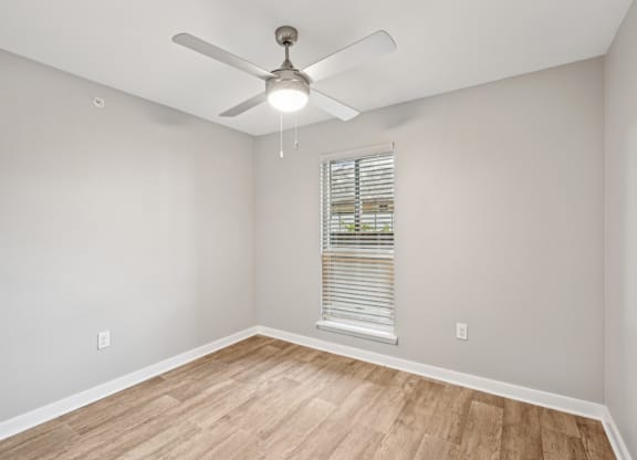 an empty room with a ceiling fan and a window