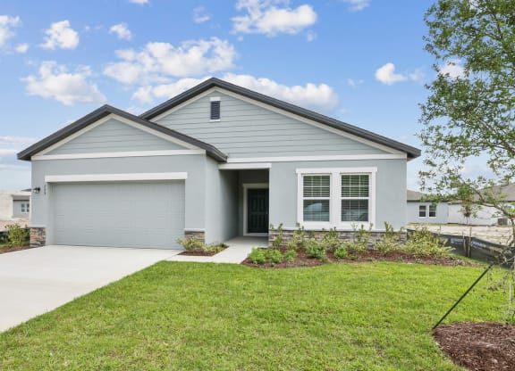a home with a gray siding and a gray garage door at Beacon at Woodland Village, DeLand, FL 32724