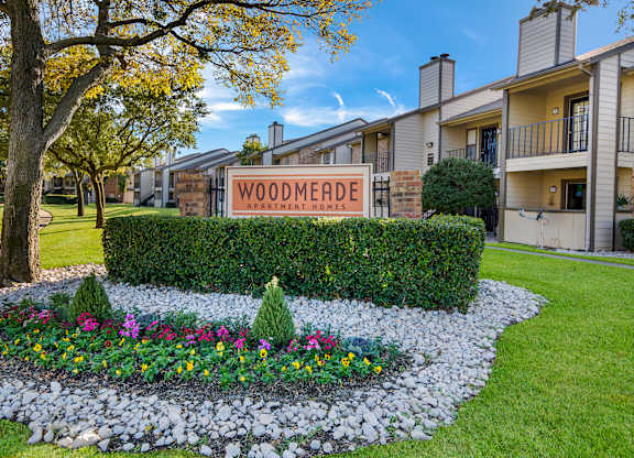 A sign that says Woodmeade Apartment Homes in front of a building.