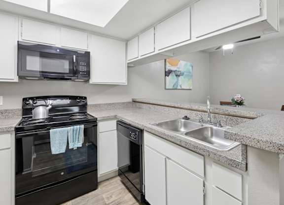 B1 kitchen with white cabinets and black appliances at Westdale Pointe in Austin, TX