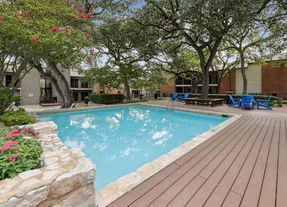 A pool surrounded by a wooden deck and trees at Westdale Pointe in Austin, TX