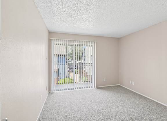 A5 bedroom with a carpeted floor and a sliding glass door leading to a balcony at Windridge on the Parkway in Dallas, TX