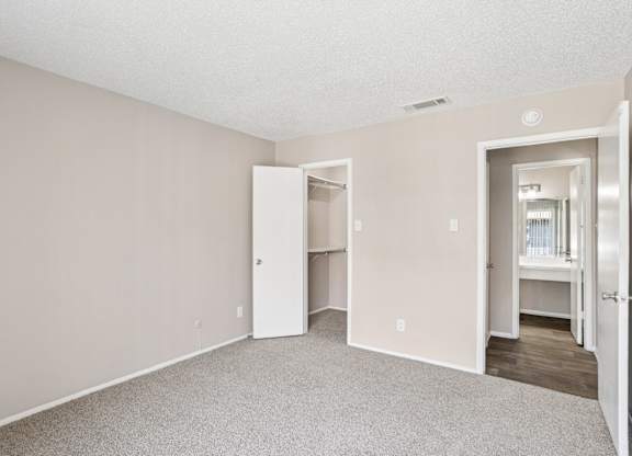 A5 bedroom looking toward the entrance and walk-in closet at Windridge on the Parkway apartments in Dallas, TX